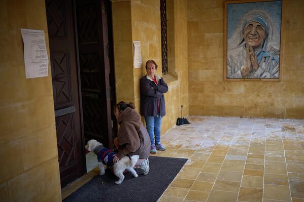 Католичка стоит на коленях рядом со своей собакой у входа в церковь в Ливане. - Sputnik Таджикистан