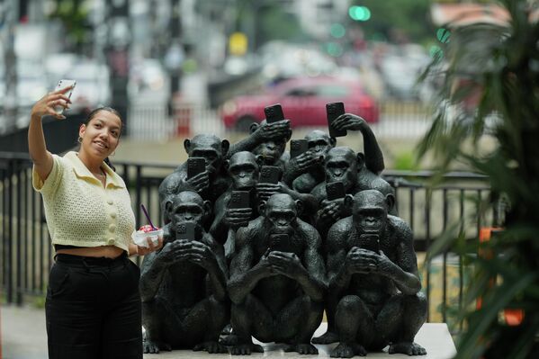 Женщина делает селфи рядом со скульптурой бразильского художника Бето Гатти на выставке "Primordios Digitais" в Сан-Паулу, - Sputnik Таджикистан