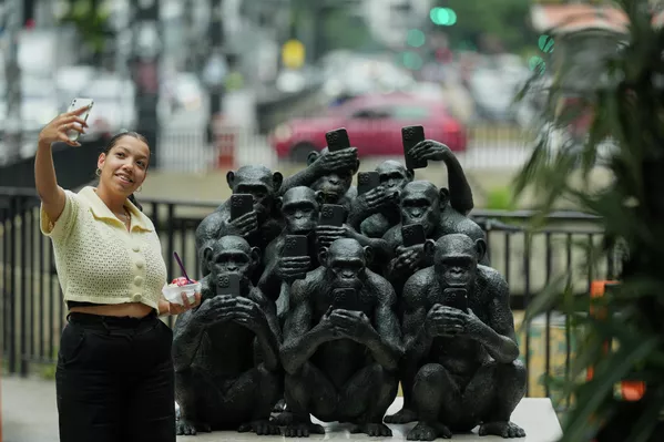 Женщина делает селфи рядом со скульптурой бразильского художника Бето Гатти на выставке 