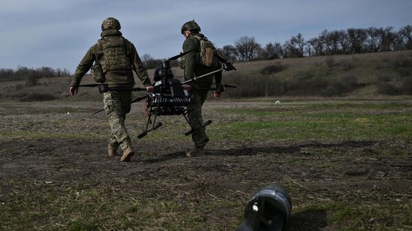 Военнослужащие 422-го полка беспилотных систем несут тяжелый ударный беспилотник перед испытательным полетом на полигоне в Запорожской области Украины 23 марта 2026 года.  - Sputnik Таджикистан