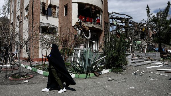 Женщина проходит мимо научно-исследовательского здания Университета Шахида Бехешти, поврежденного в результате американо-израильского конфликта в Тегеране, Иран. - Sputnik Тоҷикистон