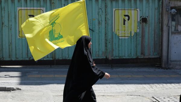 Женщина несет флаг ливанской боевой группировки Хезболла во время церемонии, посвященной 40-летию со дня смерти верховного лидера Ирана аятоллы Али Хаменеи, в Тегеране, Иран, 9 апреля 2026 года.  - Sputnik Тоҷикистон