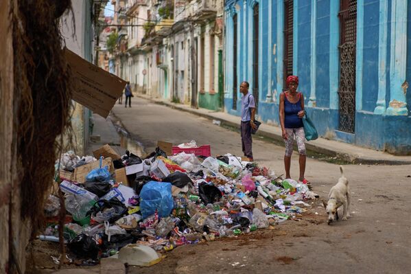 Роҳгузарон дар пасманзари партовҳо дар Ҳавана. - Sputnik Тоҷикистон