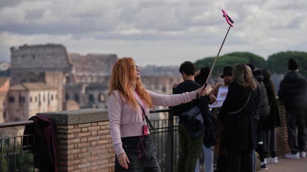 Девушка делает селфи перед Колизеем в Риме, вторник, 13 января 2026 года. - Sputnik Тоҷикистон