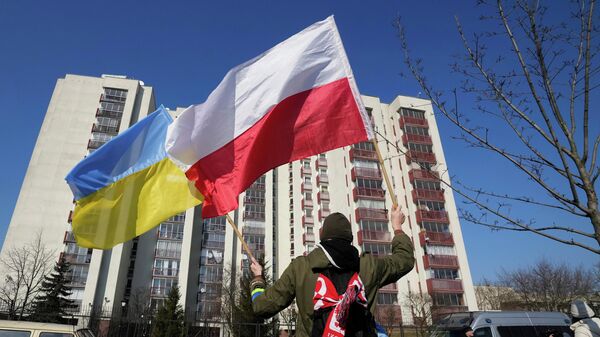 Мужчина размахивает украинским и польским флагами в Варшаве, Польша. - Sputnik Тоҷикистон
