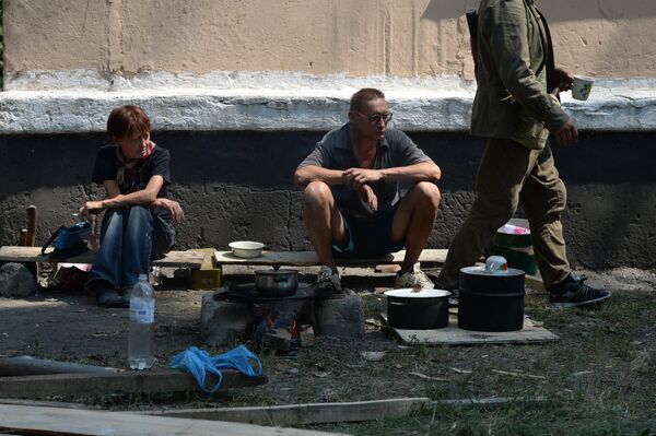 Жители Шахтерска готовят еду на костре рядом с убежищеи в подвале жилого дома. - Sputnik Таджикистан