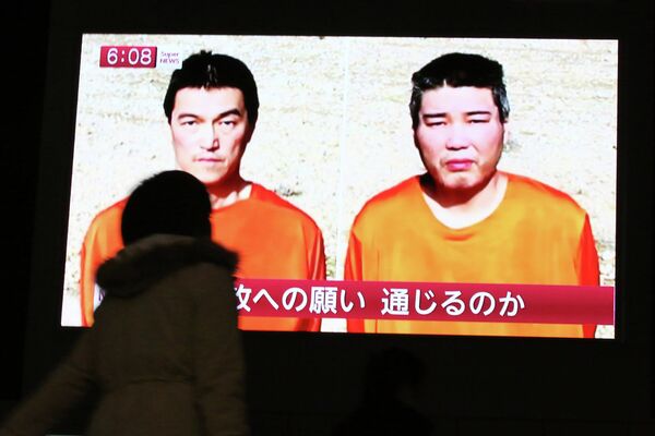 Прохожие в Токио смотрят передачу о японских заложниках, захваченных боевиками ИГ - Sputnik Таджикистан