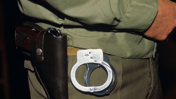 Сотрудник полиции с наручниками. Архивное фото - Sputnik Таджикистан