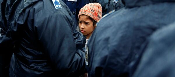 Девочка в ожидании автобуса, который отвезет беженцев в центр для лиц, ищущих убежища на юге Венгрии - Sputnik Таджикистан