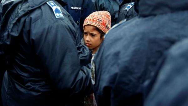 Девочка в ожидании автобуса, который отвезет беженцев в центр для лиц, ищущих убежища на юге Венгрии - Sputnik Таджикистан