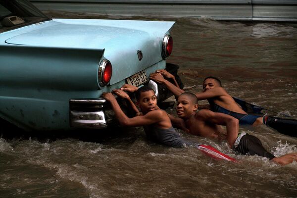 Подростки в Гаване (Куба) плывут по затопленной улице - Sputnik Таджикистан