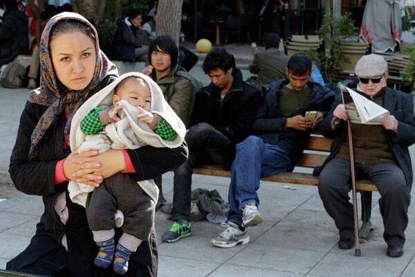 Женщина с ребенком стоит на площади Виктории в Афинах - Sputnik Таджикистан