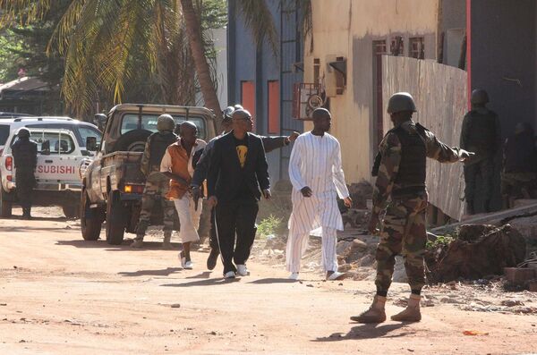 Силы безопасности сопровождают людей, бегущих из отеля Radisson Hotel Bamako, где боевики удерживают свыше полутора сотни заложников - Sputnik Таджикистан