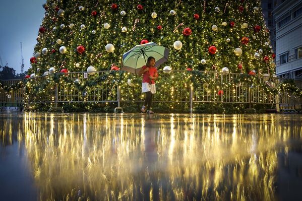 Девочка прогуливается перед большой рождественской елкой, установленной на одной из аллей в городе Куала-Лумпур - Sputnik Таджикистан