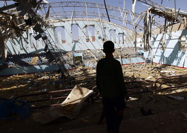 Мальчик смотрит на разрушенный спортивный комплекс в Сане (Йемен), уничтоженный в результате воздушного удара ВВС Саудовской Аравии - Sputnik Таджикистан