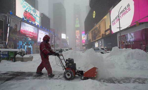 Рабочий расчищает снег на тротуаре возле площади Таймс-Сквер в Нью-Йорке - Sputnik Таджикистан