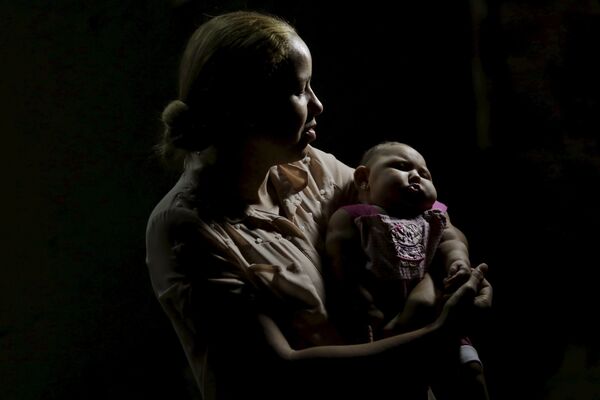 Жительница г. Ресифи (Бразилия) держит на руках свою дочь, страдающую от микроцефалии - Sputnik Таджикистан