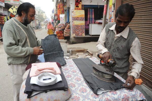 Мужчина гладит одежду угольным утюгом в Индии. Архивное фото - Sputnik Таджикистан