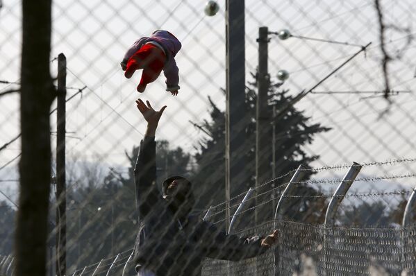Мигрант играет с ребенком в ожидании прохода через македонско-греческую границу в районе города Гевгелия (Македония) - Sputnik Таджикистан