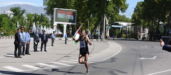 Мужчина с таджикским флагом на финишной прямой полумарафона в честь празднования Дня города в Душанбе - Sputnik Тоҷикистон