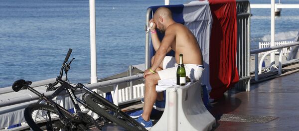 Француз скорбит возле флага страны на месте теракта - Sputnik Таджикистан