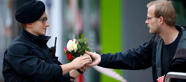 Люди приносят цветы к торговому комплексу в Мюнхене, где неизвестный убил 9 человек Люди приносят цветы к торговому комплексу в Мюнхене, где неизвестный убил 9 человек - Sputnik Таджикистан