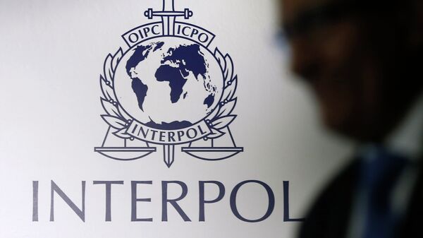 A man passes an Interpol logo during the handing over ceremony of the new premises for Interpol's Global Complex for Innovation, a research and development facility, in Singapore September 30, 2014 - Sputnik Тоҷикистон