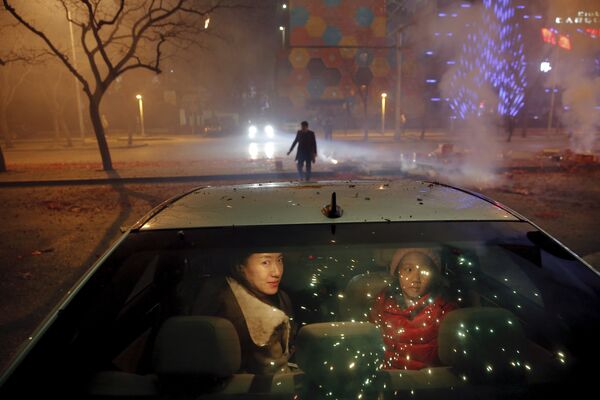 Женщина с дочкой в автомобиле во время салюта в честь наступления Нового года в Пекине - Sputnik Таджикистан