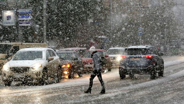 Женщина переходит улицу во время снегопада, архивное фото - Sputnik Таджикистан