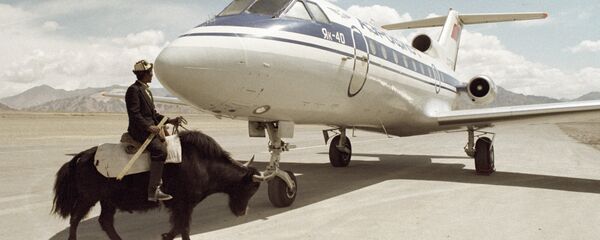 Житель Таджикистана проезжает верхом на горном яке мимо самолета Як-40, архивное фото - Sputnik Таджикистан