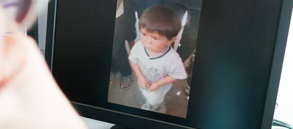 Просмотр на экране как маленький мальчик поет на одном из рынков в Таджикистане - Sputnik Тоҷикистон