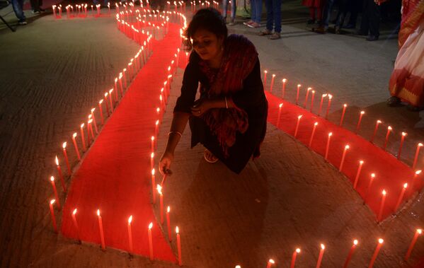 Индийский доброволец НПО освещает свечи, помещенные на землю в форме красной ленты во время всемирного дня борьбы со СПИДом - Sputnik Таджикистан