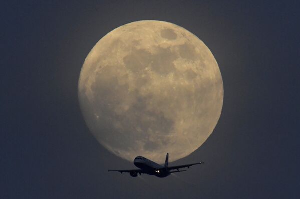 Самолет на фоне полной луны в небе над Лондоном, Великобритания - Sputnik Таджикистан
