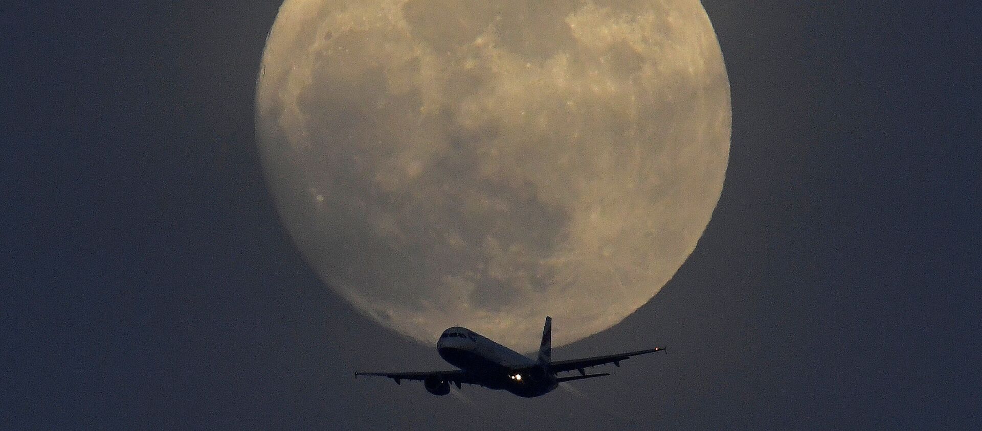Самолет на фоне полной луны в небе над Лондоном, Великобритания  - Sputnik Тоҷикистон, 1920, 29.01.2021