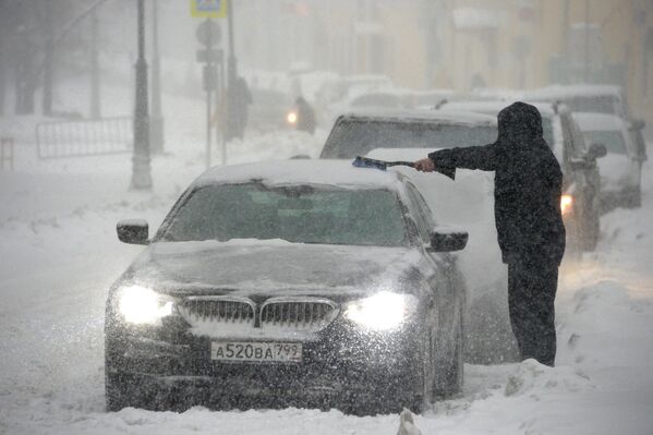 Владелец отчищает свою машину от налипшего снега во время снегопада в Москве, архивное фото - Sputnik Таджикистан