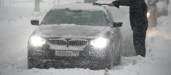 Владелец отчищает свою машину от налипшего снега во время снегопада в Москве, архивное фото - Sputnik Тоҷикистон