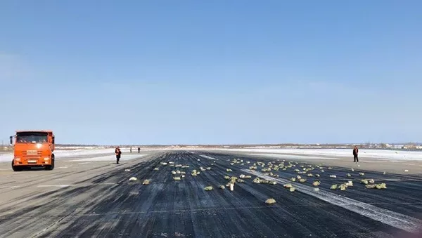Взлетно-посадочная полоса аэропорта Якутск с рассыпанным грузом из самолёта Ан-12. 15 марта 2018 - Sputnik Тоҷикистон
