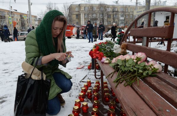 Женщина зажигает свечу возле здания торгового центра Зимняя вишняв Кемерове, где произошел пожар - Sputnik Таджикистан