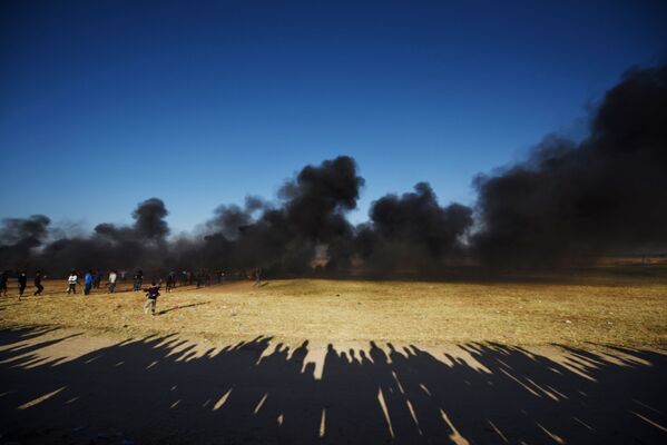 Палестинские протестующие во время столкновений с израильскими военными на границе сектора Газа и Израиля - Sputnik Таджикистан