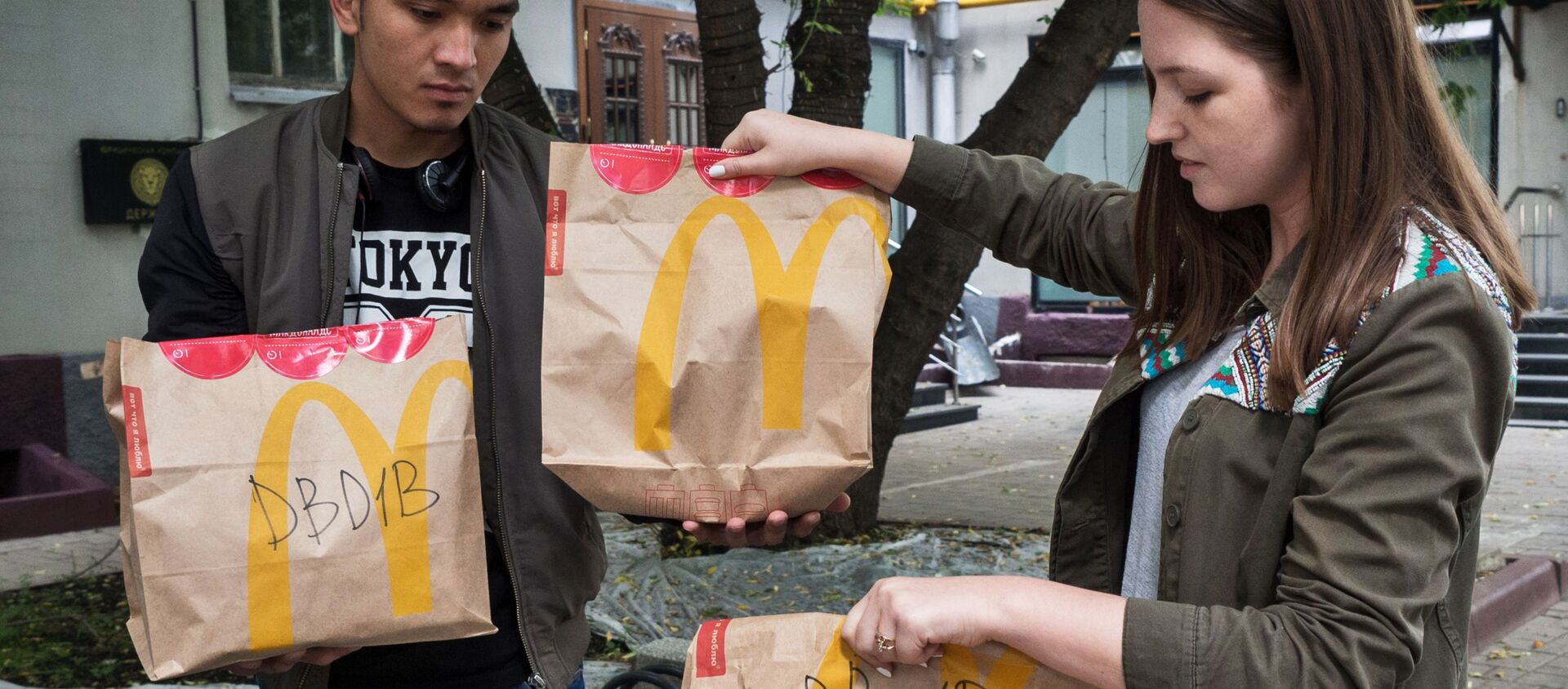 Молодые люди держат пакеты с едой из McDonald’s  - Sputnik Таджикистан, 1920, 14.09.2019