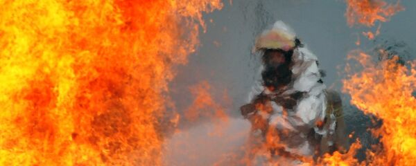 Пожарный тушит огонь, архивное фото - Sputnik Тоҷикистон