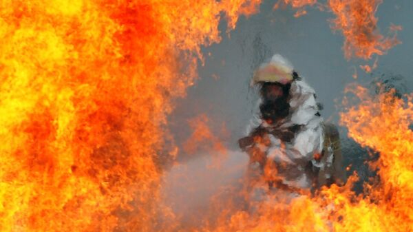 Пожарный тушит огонь, архивное фото - Sputnik Таджикистан