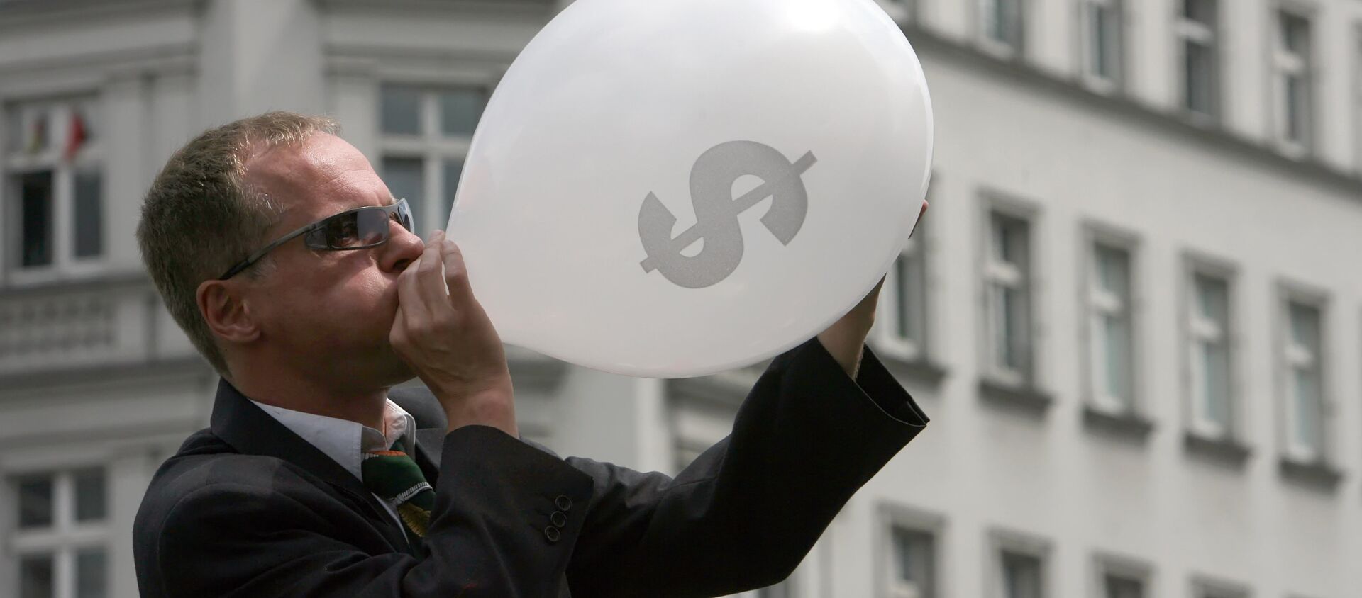 Человек в костюме надувает воздушный шар со значком американского доллара, архивное фото - Sputnik Тоҷикистон, 1920, 20.08.2019