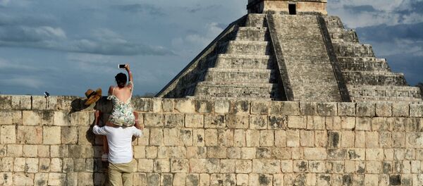 Женщина сидит на плече у мужчины и фотографирует пирамиду Чичен-Ица. Архивное фото - Sputnik Таджикистан