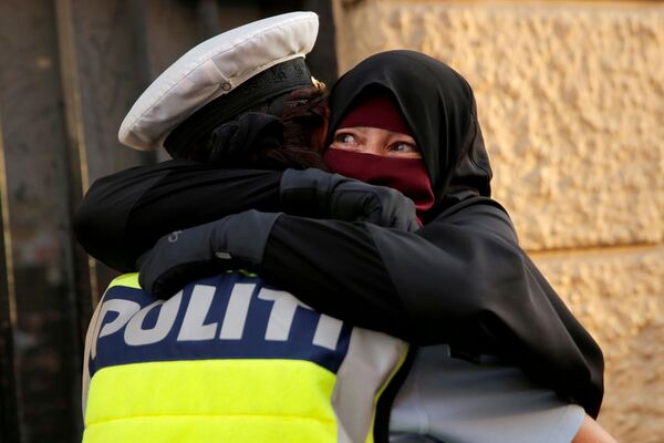Испуганная женщина обнимает полицейского во время демонстрации за запрет на ношение хиджабов в Копенгагене, Дания - Sputnik Таджикистан