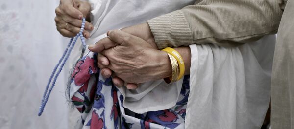 Пожилая мусульманка держит за руку своего мужа во время хаджа, архивное фото - Sputnik Тоҷикистон