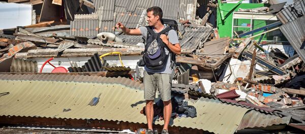 Турист пытается поймать машину после землетрясения на острове Ломбок в Индонезии - Sputnik Таджикистан