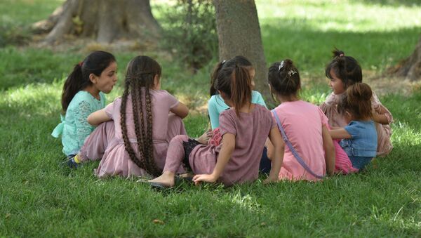 Дети сидят на траве в парке, архивное фото - Sputnik Тоҷикистон