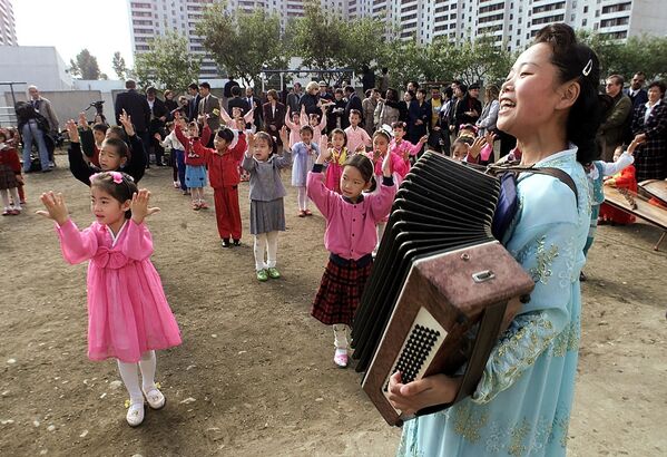 Учитель играет на аккордеоне во время приветствия госсекретаря США Мадлен Олбрайт,  в детском саду Раннанг, в Пхеньяне, Северная Корея - Sputnik Таджикистан