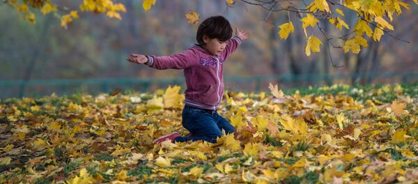 Девочка играет с опавшими листьями в парке, архивное фото Девочка играет с опавшими листьями в парке, архивное фото - Sputnik Таджикистан